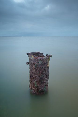Verroeste paal in het water, minimalistisch