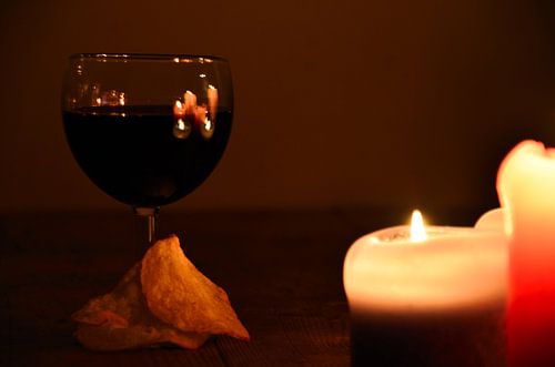 Wijn in wijnglas en chips bij kaarslicht.