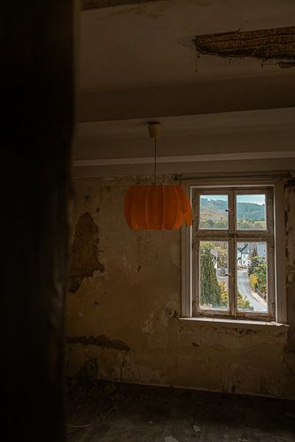 Abandoned room with orange-coloured lamp and view of the village street