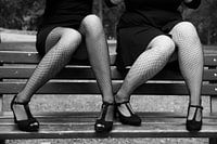 Two sexy women wearing black fishnet stockings and high heeled shoes