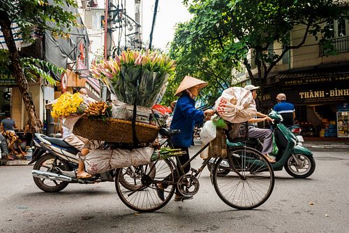 Frau mit einem Fahrrad voll von Blumen in Hanoi Vietnam