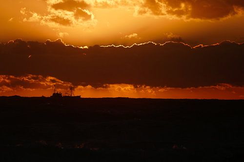 Vissersboten aan de horizon in de ondergaande zon op Texel
