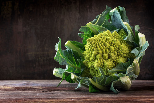 Romanesco-Brokkoli oder römischer Blumenkohl auf einem rustikalen Tisch aus dunklem Holz, das gesund