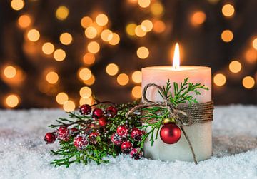 Advent en kersttijd met kaarsvlam en traditionele versiering op sneeuw van Alex Winter