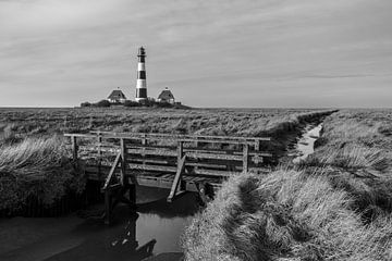 Lighthouse Westerheversand with small bridge in the salt marshes - black and white