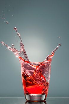 Spritzer aus einem Glas mit roter Flüssigkeit