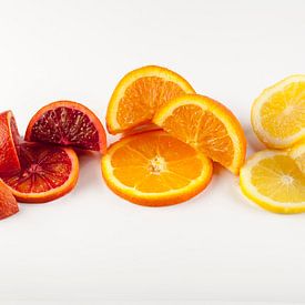 Schijfjes en partjes citrusfruit tegen een lichte achtergrond. van Ans van Heck