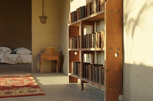 Een oude boekenkast en lemen muren, verlicht door het zonlicht van Besa Art