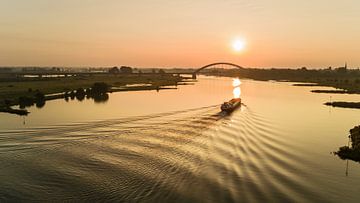 Sunrise above the Rhine in the Netherlands with ship and bridge