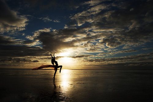 Artistiek naakt op het wad met een doek bij zonsondergang