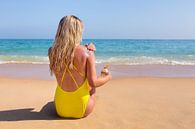 Meisje op strand smeert zonnebrandolie  van Ben Schonewille thumbnail
