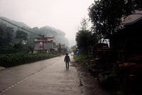 Chinese boer op regenachtige dorpsweg