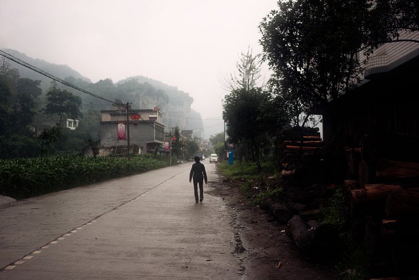 Chinese boer op regenachtige dorpsweg van André van Bel