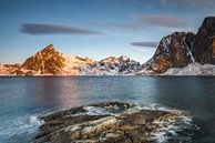 Ijsplaten op donkere rots met meer en met sneeuw bedekte steile bergen in de Reinefjord op de Lofote van Robert Ruidl thumbnail