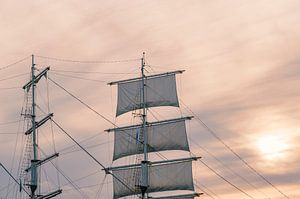 Alter Segelschiffmast und Segel bei Sonnenuntergang