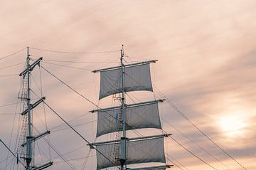 Oude mast en zeilen tijdens zonsondergang