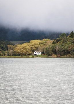Een huis aan een meer met herfstkleuren in de bomen
