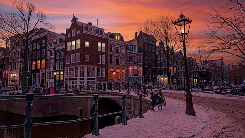 Besneeuwd Amsterdam in de winter bij zonsondergang