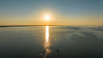 Gouden rust: Een bootje onder de stralende zonsondergang van de Oosterschelde van Lennart van Wallenburg