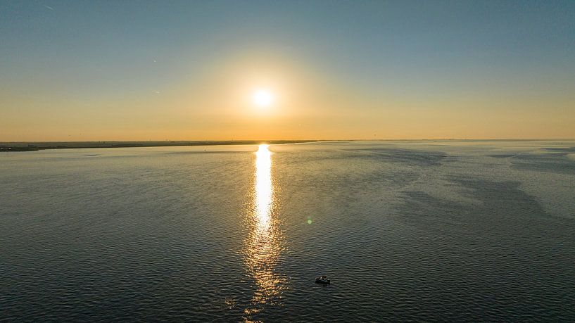 Goldene Ruhe: Ein Boot unter dem strahlenden Sonnenuntergang auf der Oosterschelde von Lennart van Wallenburg