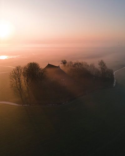 Boerderij in ochtendmist bij zonsopkomst