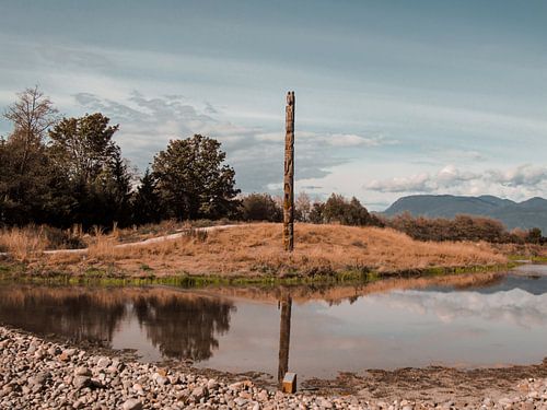 Mât totémique se reflétant dans un lac à Vancouver, Canada