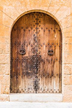 Close-up of old wooden front door with stone arch by Alex Winter