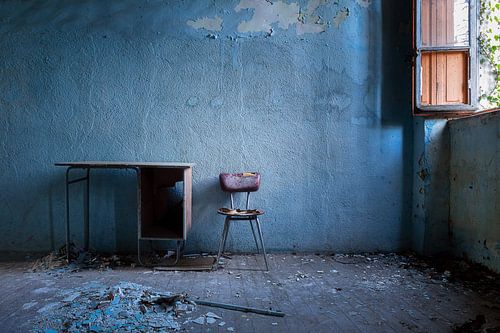 La chaise abandonnée contre le mur bleu.