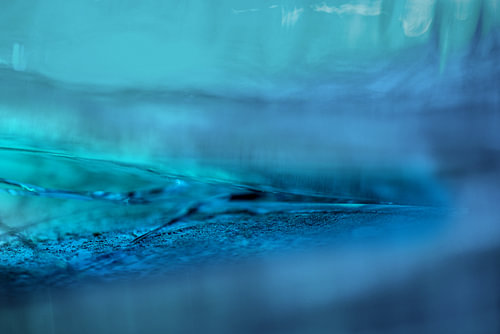 Fissures abstraites dans de l'eau gelée bleue, gros plan sur du verre et de la lumière