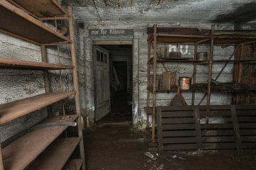 Oude stellingen met wat smeermiddel in een verlaten bunker uit WWII. van Het Onbekende