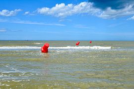 Three floating red demarcation buoys at sea