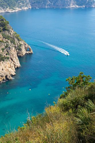 A boat glides across the blue sea water