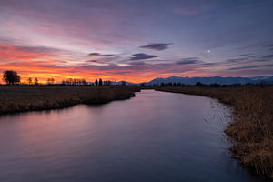 Leuchtender Morgenhimmel über dem stillen Fluss bei Uffing