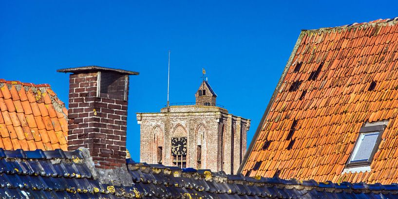 Kerk top in Elburg tussen de daken van enkele huizen. par Harrie Muis