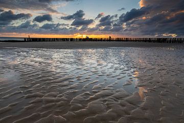 spectaculaire zonsondergang op het Zeeuwse strand met de typische Nederlandse golfbrekers