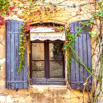 Alte Wand eines Restaurants mit Fensterrahmen und Sonnenschirmen in Südfrankreich