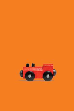 Hölzerne Spielzeugeisenbahnlokomotive auf orangefarbenem Hintergrund von Anton Hammenecker