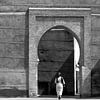 Vrouw loopt door een poort in het centrum van Marrakech van Evelien Oerlemans
