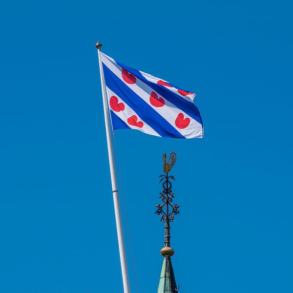 De Friese vlag en de kerktorenspits van het dorpje Cornwerd by Harrie Muis