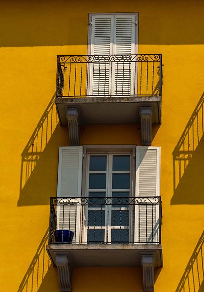 Balkons tegen gele muur met schaduw van Martine Moens
