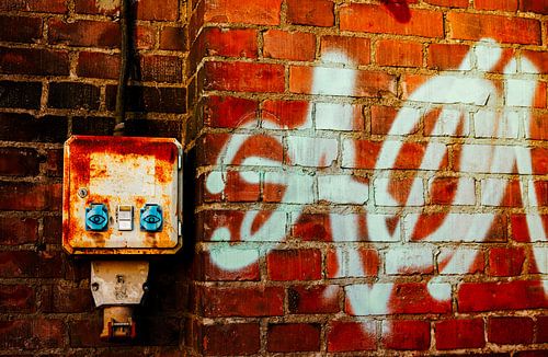 Bakstenen muur met graffiti & roestige stroomkast – urban industriële muurkunst