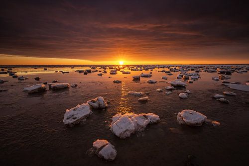 De Waddenzee is bedekt met IJsschotsen in de winter. Een mooie zonsondergang geeft prachtige kleuren