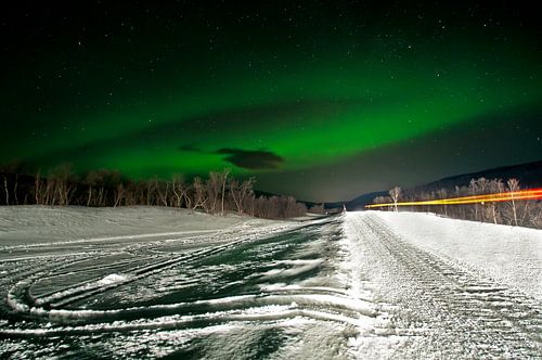 Noorderlicht boven een winterse weg in Noorwegen van Anjo Kan