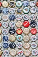 Varied collection beer bottle caps glued on a wall 