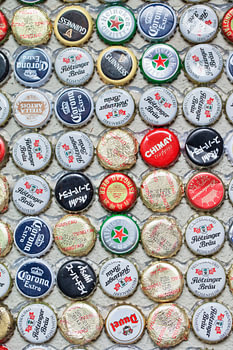 Varied collection beer bottle caps glued on a wall 