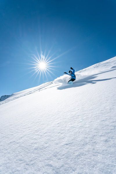 Snowboarders in powder snow in sunshine and powder snow by Leo Schindzielorz