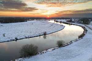 Vecht river flowing through a snowy winter landscape during sunset