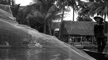 Un pêcheur jette un filet de pêche sur la rivière