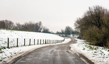 Landweg in een sneeuwlandschap sur Ruud Morijn