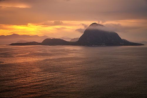 Rock in the ocean with clouds in sunrise near Alesund in sunrise atmosphere
